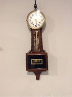 Front view of complete banjo-style Ingraham wall clock mounted on wall