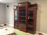 Full frontal view of the large wooden wall unit showing three glass doors, crown molding and lower drawer section