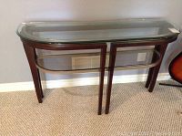 Full view of hall table showing glass top, glass lower shelf, and wooden frame with curved front edge.