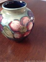 Close-up view of the vase showing floral hand-painted decoration on cream background with visible crackle glaze and deep blue interior.