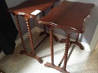 Pair of wooden side tables with visible spindle legs and scalloped tops, standing on carpeted floor.