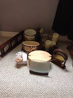 Decor items including ceramic planters, glass vases, pillar candles, brass animal figurines, wooden picture frames, and a brass gong on carpeted floor.