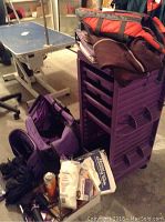 Photo showing purple rolling cart with multiple drawers and grooming accessories placed on it, including a red and black life jacket, grooming bags, and brushes.