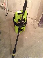 Front angled shot of the green and black power washer with its hose wrapped around and attached spray gun laid across the front.