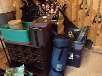 General overview of the lot showing plastic storage bins, cooler bag, camping mattress, shoe rack, and bags