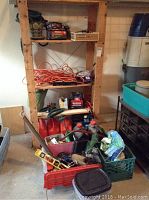 Wood shelving unit with various maintenance and garden items including extension cords, gasoline cans, and storage crates.