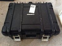 Closed black Husky tool box with silver metal latches on front and a label sticker.