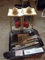 Pair of metal lanterns with cream tops and red decorative ornaments inside, along with a box of Bliss decorative wall tiles on the floor.