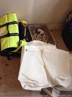 Four white nylon fender bags, large dog life jacket, and flotation devices in tote and on floor
