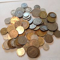 Photo showing a pile of various Middle Eastern coins with denominations and inscriptions in Arabic and other regional scripts, made of different metals.