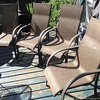 Six brown mesh sling patio chairs with dark metal frames, arranged outdoors on a deck, showing the chairs' design and condition.
