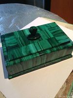 Overall external view of closed box showing rectangular shape, polished banding, knob and corner feet