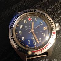 Close-up front view of a vintage Russian mechanical wristwatch with blue dial, red star, and date window.