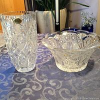 Two Bohemia lead crystal items on a patterned tablecloth, a tall vase and a decorative bowl.