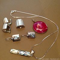 Sterling silver jewelry including pendants and earrings arranged on surface, showing the Murano glass pendant and mother of pearl inlays