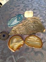 Photo of six polished rock center samples showing a variety of natural patterns, colors, and shapes on a textured cloth background.