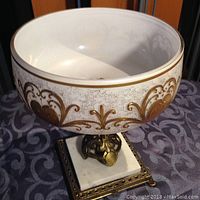 Front and side view showing ornate gold decorative pattern on a white bowl mounted on a marble base with brass pedestal.