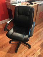 Front view of black leatherette office chair showing padded seat, backrest, and armrests.