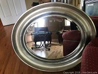 Front view of the oval beveled glass wall mirror showing overall shape and reflective surface with brushed metallic frame.
