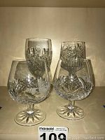 Four crystal stemware glasses including Galway snifters with Claddagh motif and two wine glasses from Waterford and Galway.