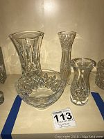 Overall view of two Waterford crystal vases, one Waterford crystal bowl, and a Tyrone bud vase arranged on a shelf.