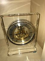 Front view of the Hoya crystal quartz clock showing the clear rectangular body and visible inner mechanism with Roman numeral face.