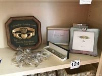 Display of various pins, sterling silver rings in box, picture frames including one heart shaped frame, and a wooden framed cast iron plaque with 'Friendship, Loyalty, Love' theme on shelf