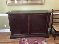 Full front view of the dark stained wooden buffet with detailed carved doors.