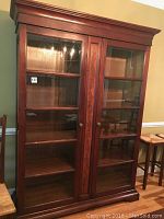 Full view of the china cabinet showing wooden frame, glass doors, and shelving inside.