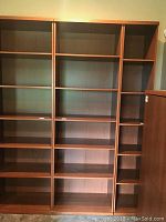 Front view showing full height and six shelves with warm brown finish.