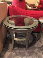 Side view of metal frame with circular glass top showing legs and lower support ring.