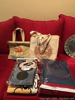 Disney throws, quilt, and three tote bags displayed on red couch