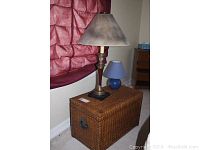 Wicker trunk with the two included lamps placed on top, showing the full setup and room context.