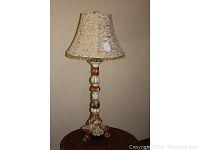 Full view of the 42-inch ornate midcentury table lamp with fabric shade and fringe trim
