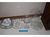 Full view of 11 glass and crystal platters and bowls arranged on floor, showing variety of clear and floral-design pieces.