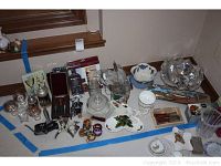 Full array of items arranged on floor including wine accessories, cheese knives, covered cheese dish, crystal vase, and serving dishes.