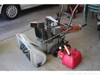 Snowblower and red fuel can side by side in garage