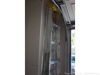 Photo of Werner extension ladder folded and leaning against a wall inside a garage.