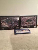 Three framed Colorado Rockies memorabilia pieces displayed on floor with two large aerial photos of Coors Field and a smaller framed image below.