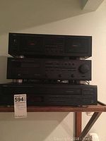 Full view of Yamaha stereo system components stacked on a wooden shelf, including double cassette deck, stereo receiver, and CD player.