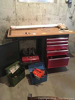 Red Craftsman tool bench with drawers open, vintage GE speakerphone on top surface, and containers with tools and power tools on floor.