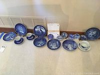Wide view of all plates, cups and paperwork arranged on floor showing blue and white Danish collectible items