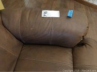 Medium dark brown leather couch armrest showing stitching and leather texture with auction tag.