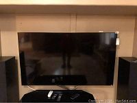 Front view of Vizio 70" TV on wall mount with remotes on console below