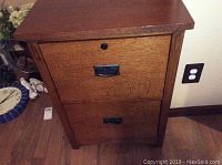 Front view of the wood filing cabinet showing two drawers with metal handles and a lock on the top drawer.