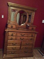 Front view of oak wood dresser with attached oval mirror and decorative side mirror panes, showing overall design and condition.