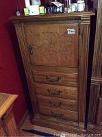 Full view of the tall wood cabinet showing door and drawers.