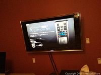 Wall-mounted TV powered on against red wall, center view