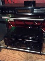 Wide view of two stacked audio components showing model and brand details with cables behind.