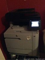 Front view of HP Laserjet multifunction printer showing the touchscreen control panel and paper trays.